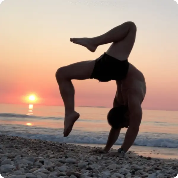 Man doing handstand on a beach during a sunset